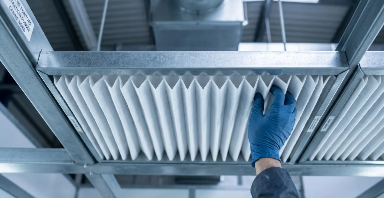 Gros plan d'un filtre plafond de cabine de peinture avec média filtrant plissé blanc visible, installé dans son cadre métallique